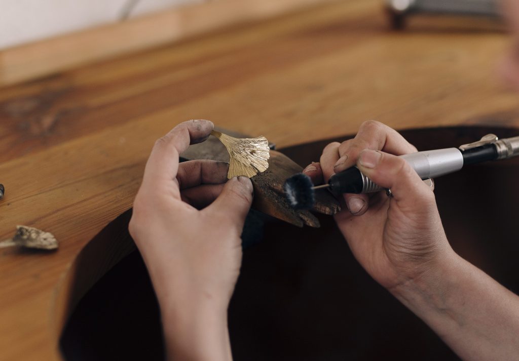 Travail de polissage d’un bijou en forme de feuille à l’atelier Amabilis